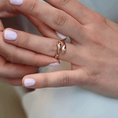 Detail view of a woman’s finger adorned with a tiny hands rose gold hug ring