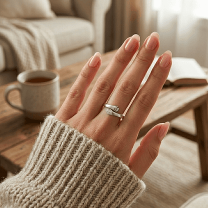 Detail view of a woman’s finger adorned with a tiny hands silver hug ring