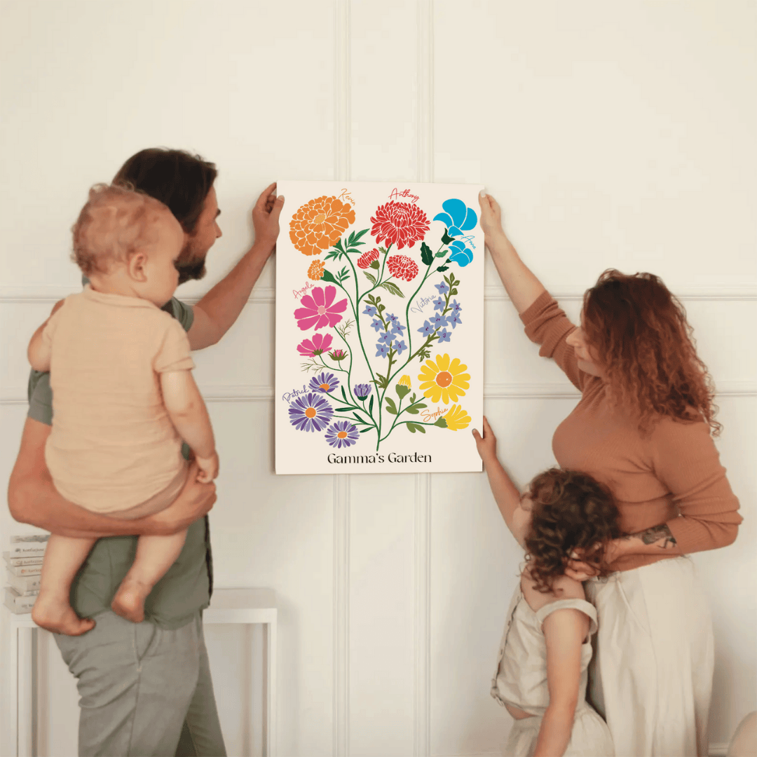 A family of four works together to hang a "Gamma's Garden" birth flower canvas on a living room wall