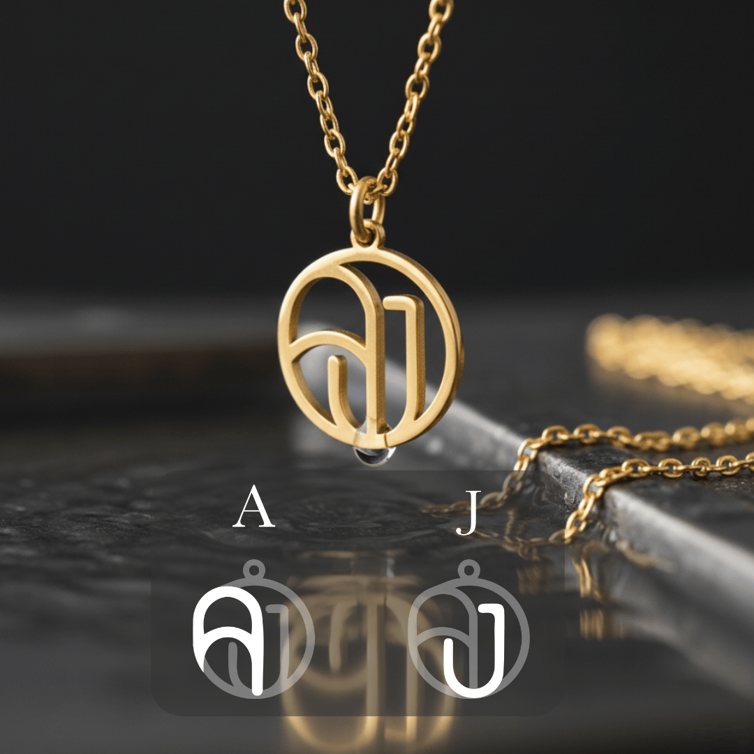 Gold monogram necklace hanging against dark background 
