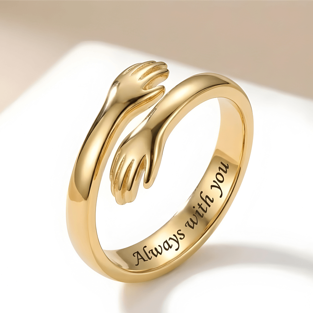 Close-up of a gold adjustable hug ring with small hands design, engraved with "Always with you"