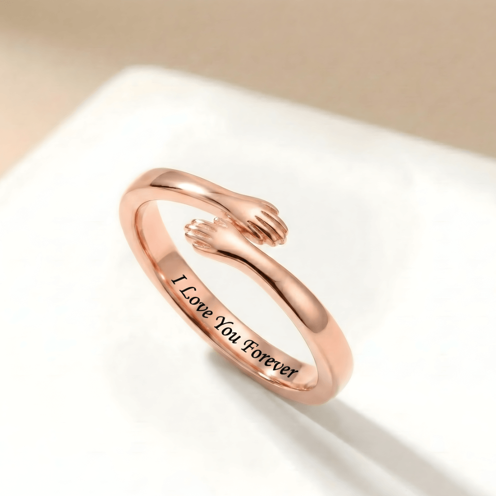 Close-up of a rose gold adjustable hug ring with small hands design, engraved with "I love you forever