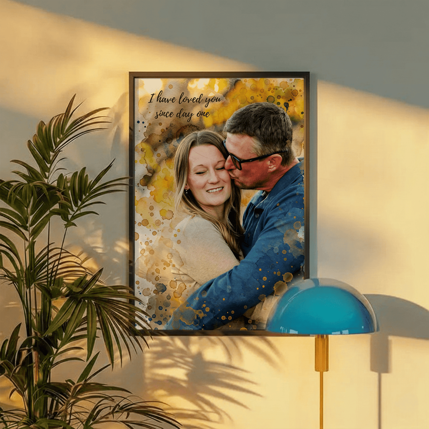 Framed personalized portrait of an older couple embracing, with yellow and blue watercolor accents, next to a plant and a blue lamp.