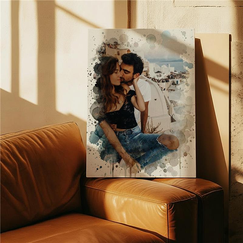 Personalized watercolor canvas of a couple embracing with a white Greek village backdrop, featuring blue and gray paint splatters, leaning on a brown leather couch.