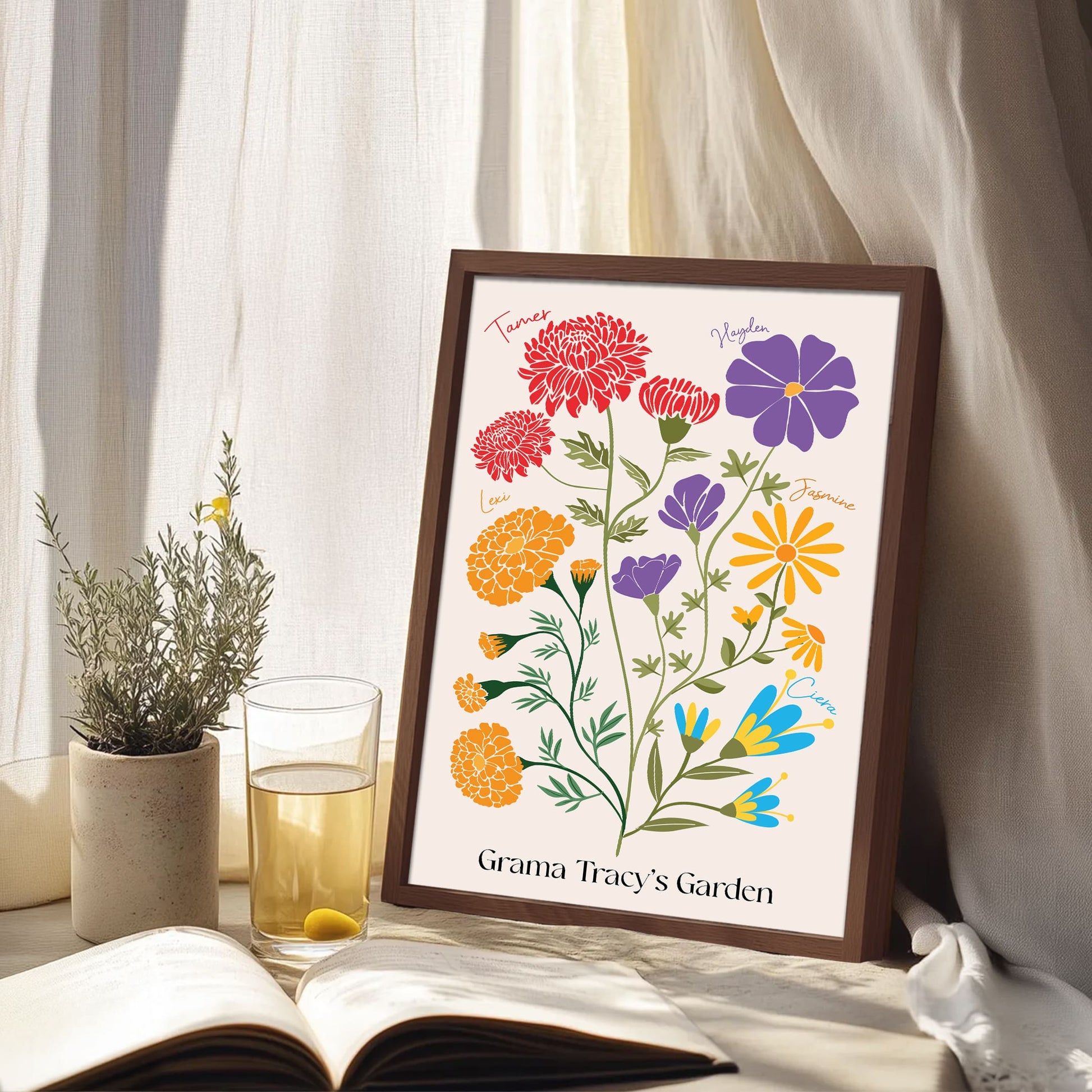 A framed "Grama Tracy's Garden" birth flower print featuring family names like Lexi and Ciera, displayed on a windowsill with a book and a glass of water.