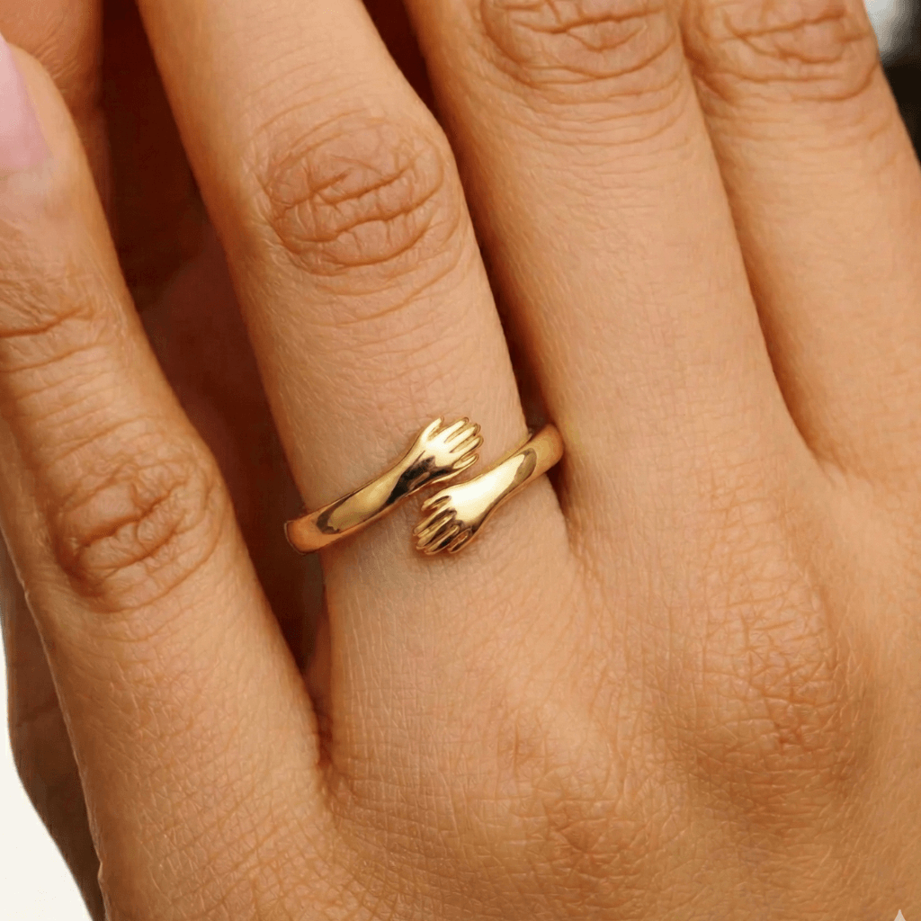 Close-up of a gold adjustable hug ring with small hands design on a woman's hand 
