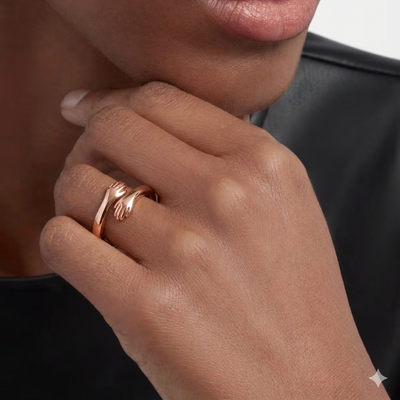 Rose gold adjustable ring with delicate hand design, close-up on finger