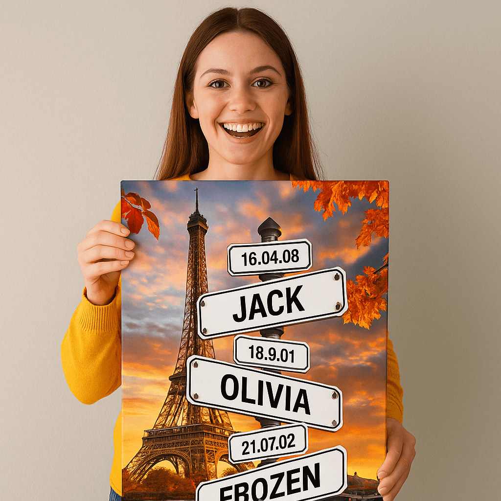 A smiling woman in a yellow sweater holds a canvas featuring the Eiffel Tower at sunset with street signs displaying names like "JACK," "OLIVIA," and "FROZEN" along with significant dates.