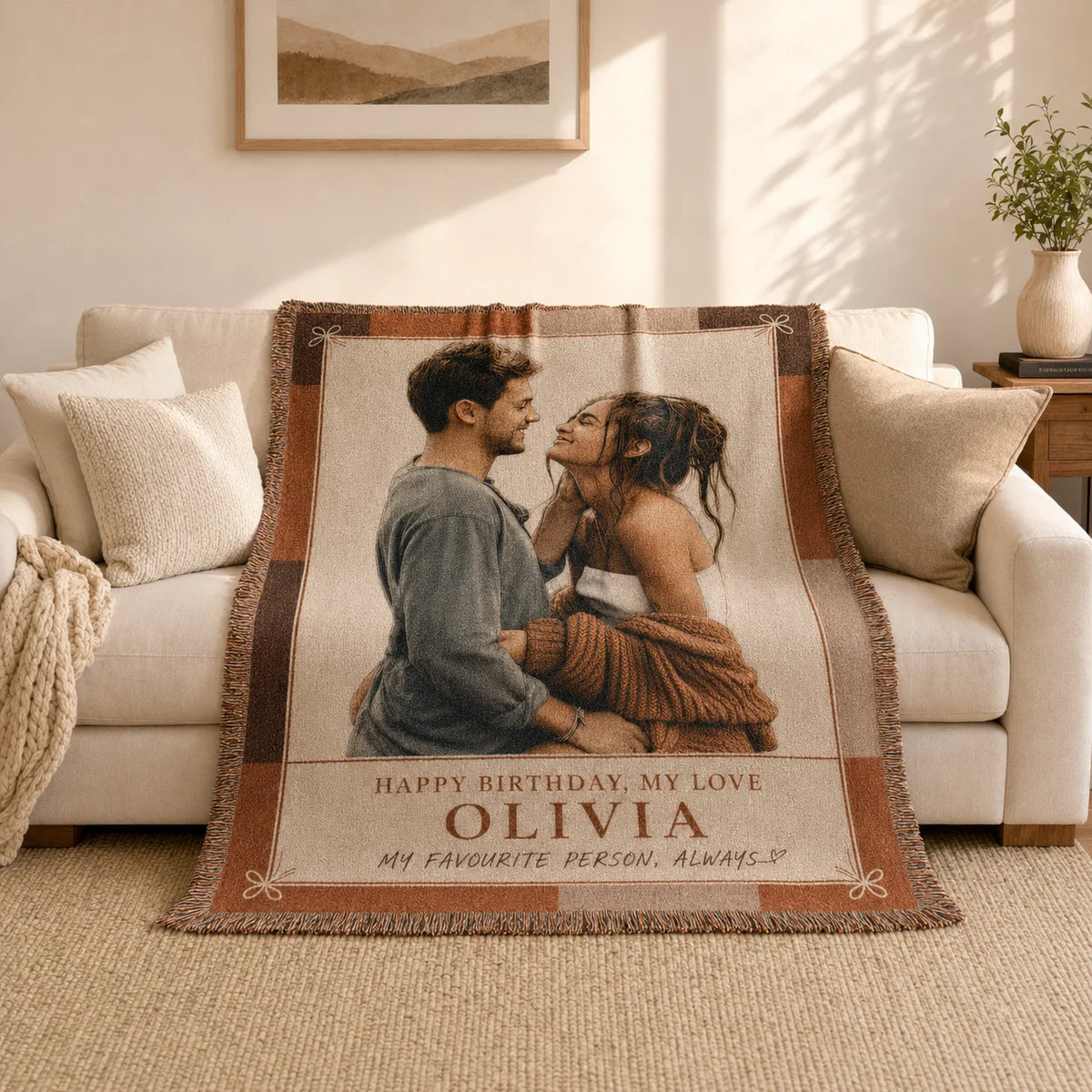 Personalized birthday woven blanket in the Birthday Love terracotta design on a sofa, with a woven birthday message and name