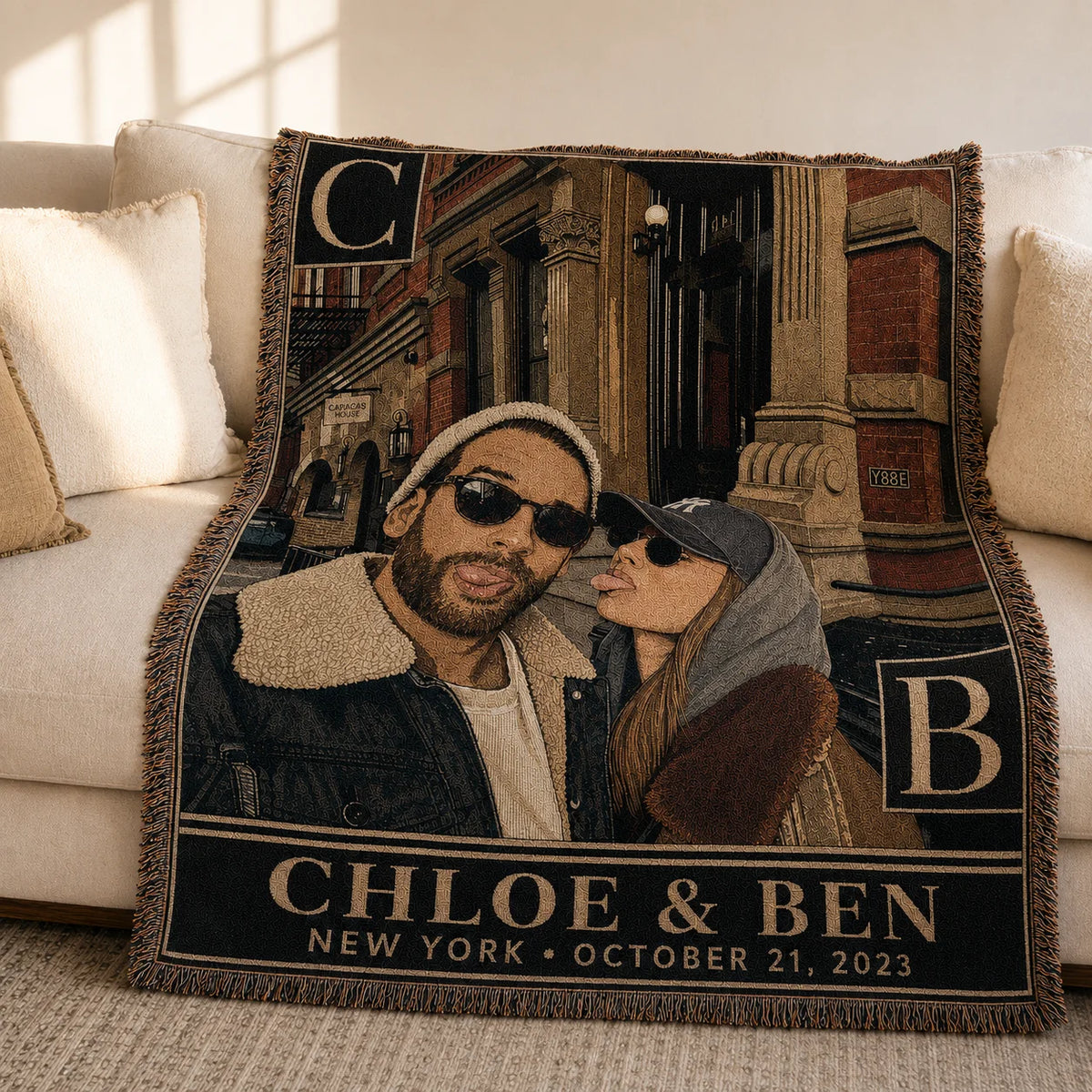 Personalized couple woven blanket in the Monogram City design on a sofa, with bold initials, names, city and date