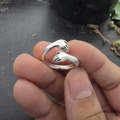 Close-up of a man holding an adjustable gold ring with small hands hugging