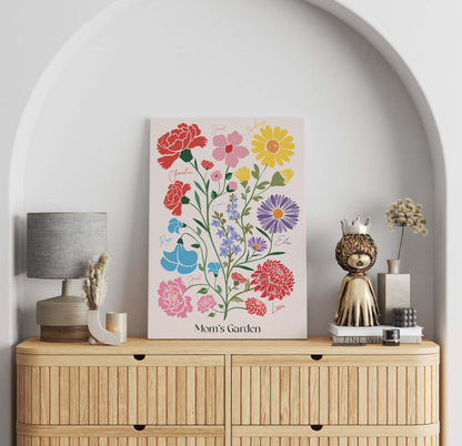 A framed "Mom's Garden" birth flower art piece displayed on a wooden dresser alongside a lamp and decorative gold figurine.