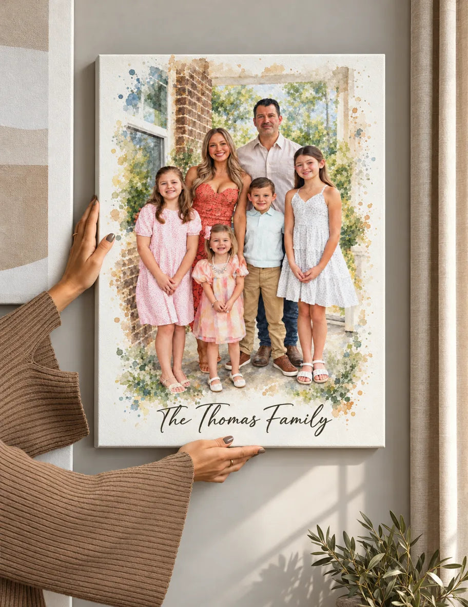 Hands hang a canvas watercolor portrait of two parents and three kids on a wall.