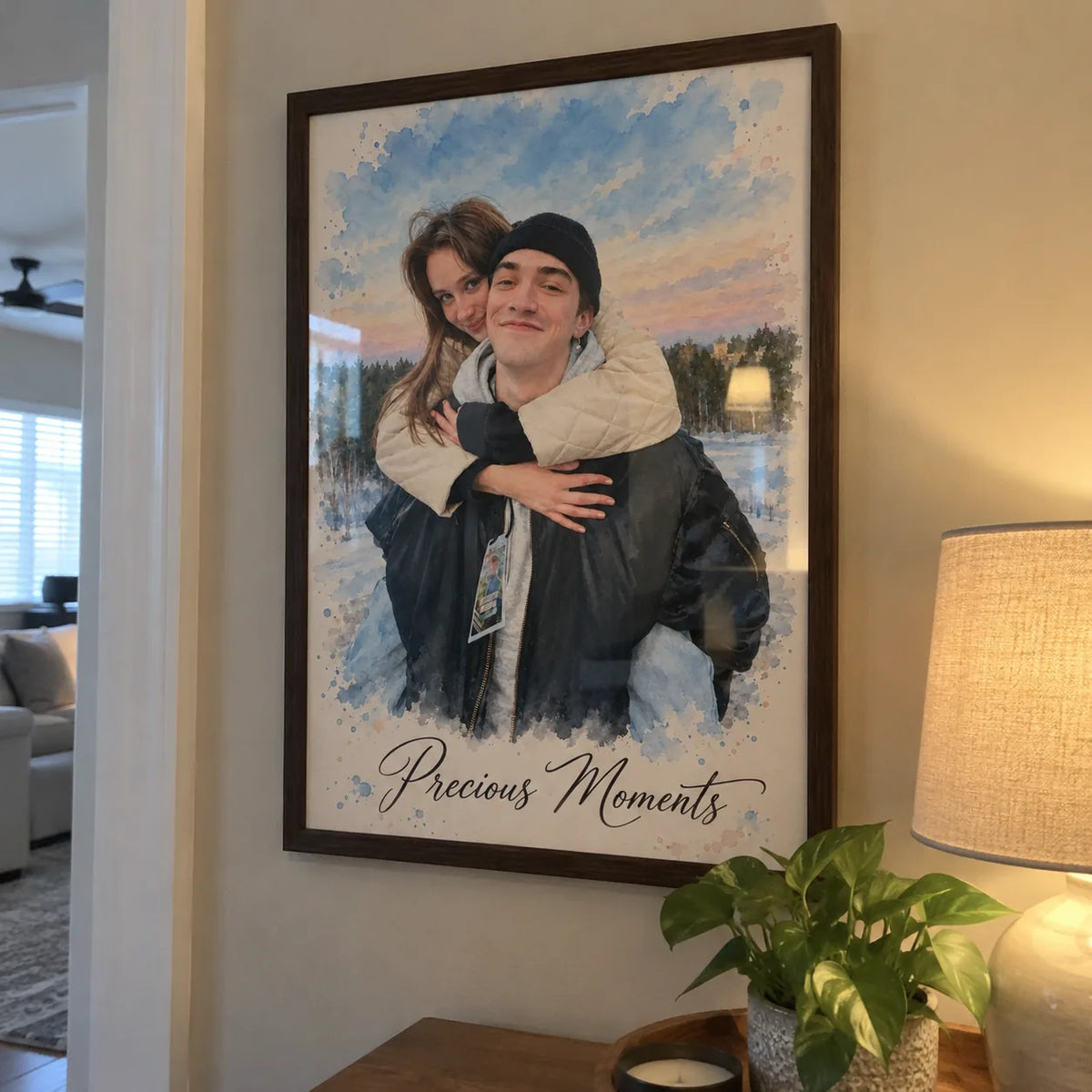 A framed watercolor portrait of a couple in winter hangs on a wall next to a lamp.