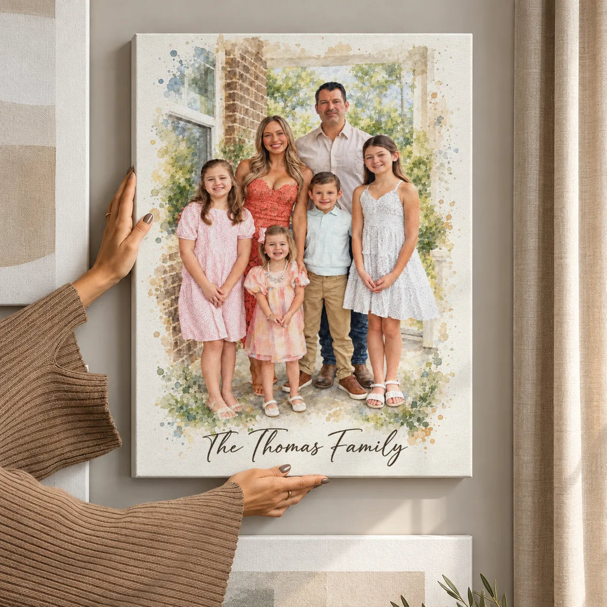 Hands hanging a canvas watercolor portrait of two parents and three girls
