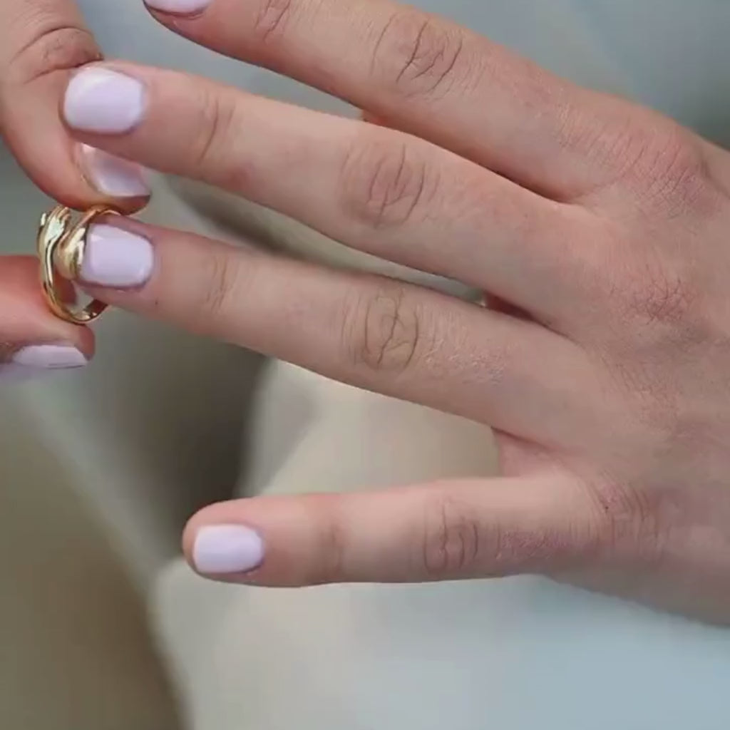 Detail view of a woman’s finger adorned with a tiny hands gold hug ring